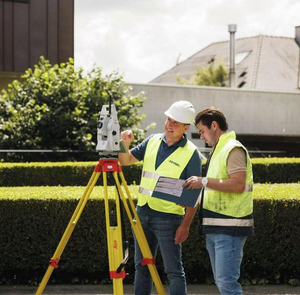 Twee landmeters van Sabbe overleggen naast een totaalstation op statief