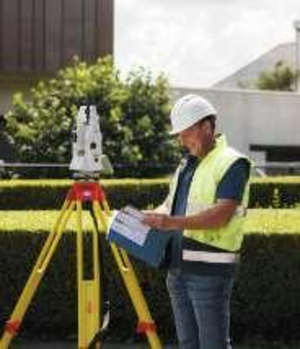 Landmeter met helm en fluohesje bij een Leica totaalstation op statief met plan in de hand