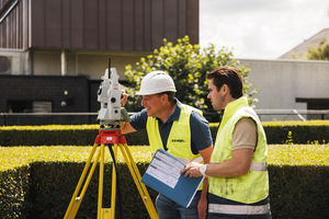 Twee landmeters van Sabbe overleggen met een plan naast een totaalstation
