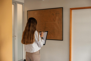 Medewerkster noteert gegevens op een tablet in een gang tijdens een plaatsbeschrijving
