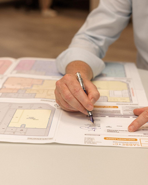 Hand die met een vulpen tekent op een opmetingsplan